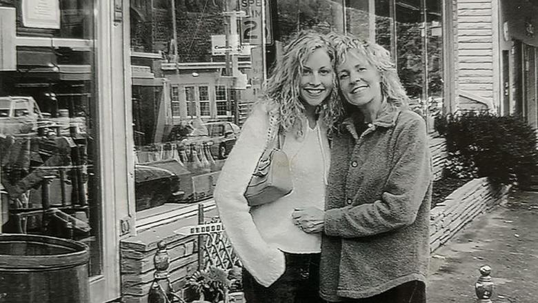 两个女人手挽着手站在一家商店外面